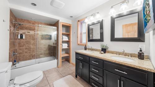 Un baño con dos lavabos y una ducha. en Sweet Pine Deck Hot Tub Cozy Modern Interior Close to Ski Resort, en Pomins