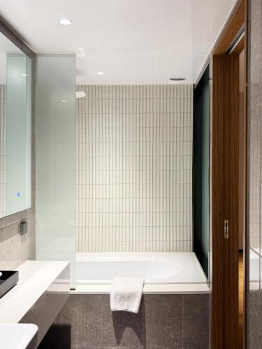 a bathroom with a tub and a glass shower at Ibis Ambassador Suwon in Suwon