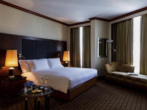 a hotel room with a large bed and a couch at Pullman Khon Kaen Raja Orchid in Khon Kaen