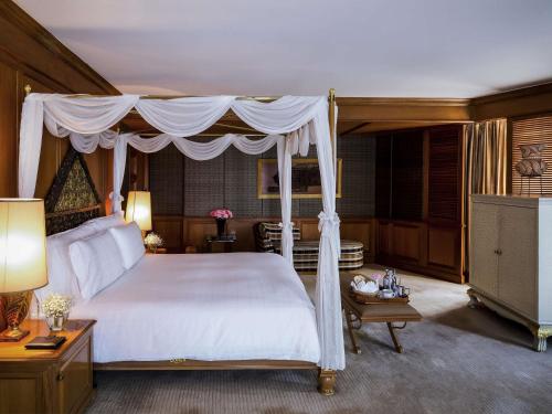 a bedroom with a white bed with a canopy at The Heritage Grand Khon Kaen Hotel and Convention in Khon Kaen
