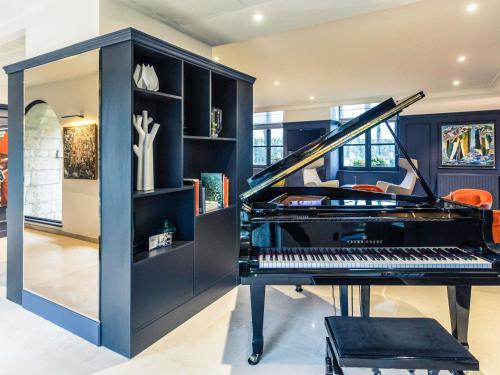 una stanza con pianoforte e libreria di Hotel De Bourbon Grand Hotel Mercure Bourges a Bourges
