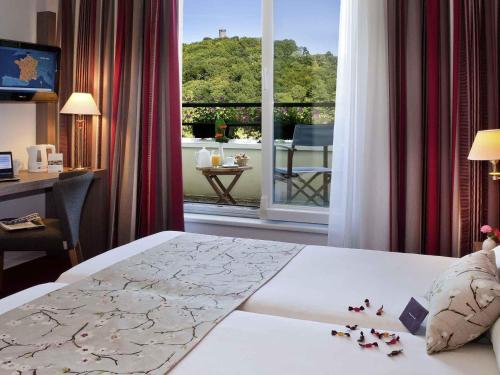 a hotel room with a bed and a view of a balcony at Mercure Hotel Forbach Centre de Loisirs in Forbach