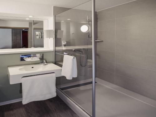 a bathroom with a sink and a shower at Mercure Hotel Forbach Centre de Loisirs in Forbach