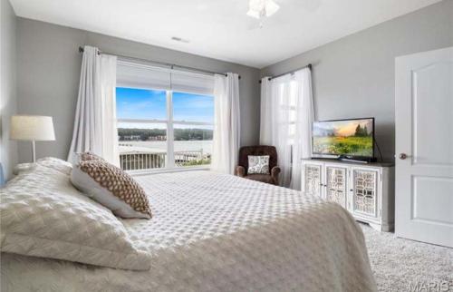 Un dormitorio con una cama grande y una ventana grande en 3BD 3BA Gated Condo LakeFront Lake Ozark, MO Isla Del Sol 4 M from Dam, en Rocky Mount
