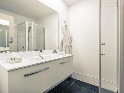Un baño blanco con lavabo y ducha. en Mercure Queenstown Resort, en Queenstown