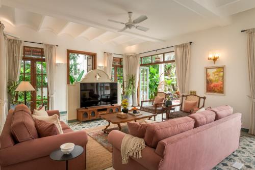 a living room with pink couches and a tv at La Dona by The Blue Kite - 4BHK Private Pool Villa in Assagao with Garden, Balcony, Caretaker & Spacious Living Area in Assagao