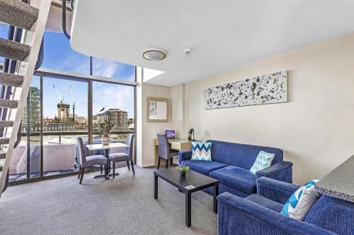 a living room with a blue couch and a table at Metro Apartments on Darling Harbour in Sydney