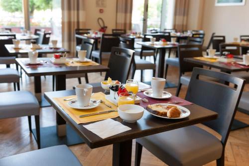 een restaurant met tafels en stoelen met eten erop bij Grand Hôtel Filippo Strasbourg Nord in Niederbronn-les-Bains