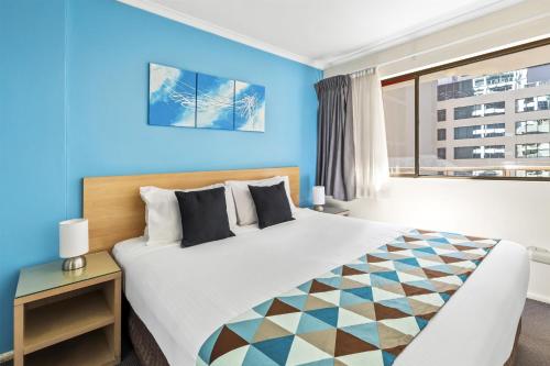 a bedroom with a large bed with a blue wall at Metro Apartments on King in Sydney
