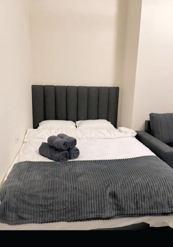 a bed with a black headboard and towels on it at Apartment tsaghkadzor SHINE HOME in Tsaghkadzor