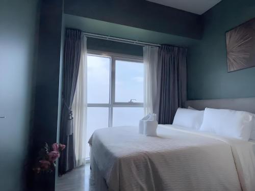 ein Schlafzimmer mit einem weißen Bett und einem Fenster in der Unterkunft 90 Sqm Perfect Seaview Luxurious Modern 2 Bedrooms, Nearby Okada, Solaire, Airports, MOA with Free Parking in Manila