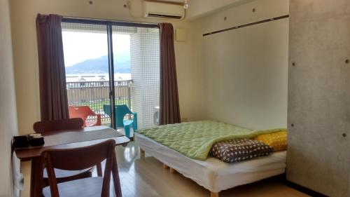 a bedroom with a bed and a window with a balcony at Gracias in Kagoshima