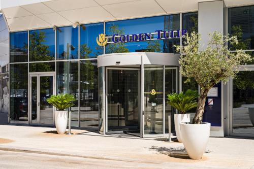 a building with two potted plants in front of it at Golden Tulip Marseille Euromed in Marseille