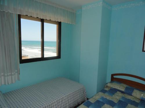 a bedroom with a bed and a window with the beach at Apartamentos Raymar in Oropesa del Mar