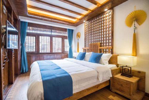 a bedroom with a large bed with blue and white sheets at Lijiang Yue Tu Inn in Lijiang