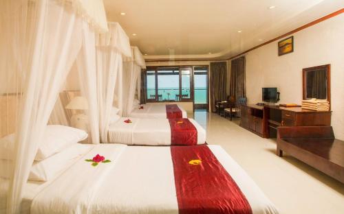 a hotel room with two beds and a television at Rock Water Bay Beach Resort & Spa in Xóm Tram