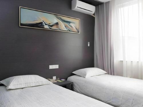 a bedroom with two beds and a painting on the wall at Goodrich Hotel in Hong Kong