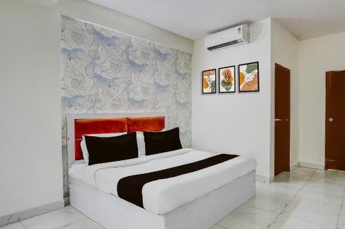 a bedroom with a white bed with a red headboard at Super Hotel O Sector 51 Metro Station Formerly Shubham Residency in Indirapuram