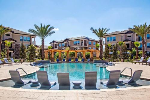 a swimming pool at a resort with chairs and palm trees at Landing Incredible 1BD Gym Clubhouse in Klein