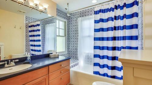 Cottage by the Pool by AvantStay w Balcony BBQ Shared Pool Month Long Stays Only في ستوك آيلاند: حمام به ستارة دش زرقاء وبيضاء