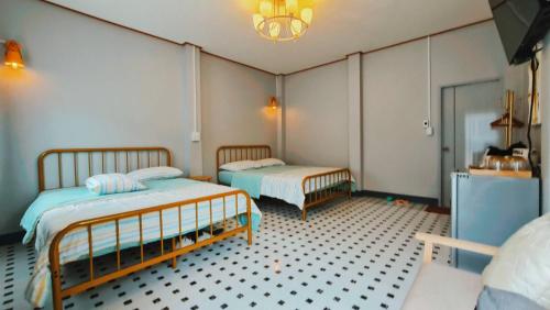 - une chambre avec deux lits et du carrelage dans l'établissement โฮมสเตย์ ยายหนั่น, à Chaiyaphum