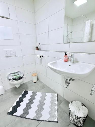 a white bathroom with a sink and a toilet at Stilvolles Apartment mit Balkon - zentrumsnah, self checkin in Augsburg
