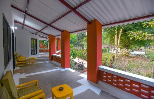 a porch with orange columns and chairs and a garden at Tala Camp in Tāla
