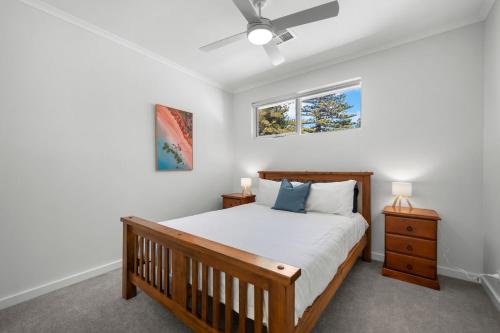 a bedroom with a wooden bed and two windows at Belle Escapes - Henley Beach House in Henley Beach