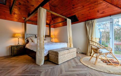 une chambre avec un lit à baldaquin et une chaise dans l'établissement Lakeside haven cottage - Macedon ranges, à Riddell