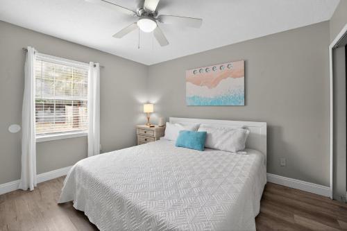 une chambre blanche avec un lit et un ventilateur de plafond dans l'établissement Luxury Beach Access, à Panama City Beach