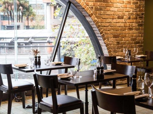 un ristorante con tavoli e sedie e un muro di mattoni di Mercure Sydney a Sydney