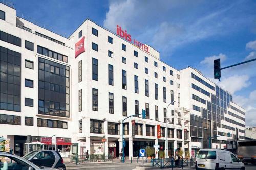 Un gran edificio blanco en una calle de la ciudad con un semáforo. en ibis Paris Pantin Eglise, en Pantin