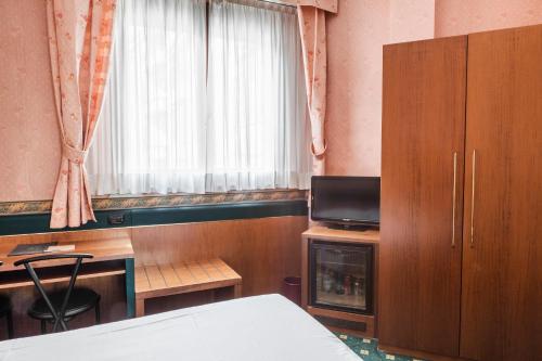 a bedroom with a bed and a desk and a window at Hotel Des Etrangers in Milan