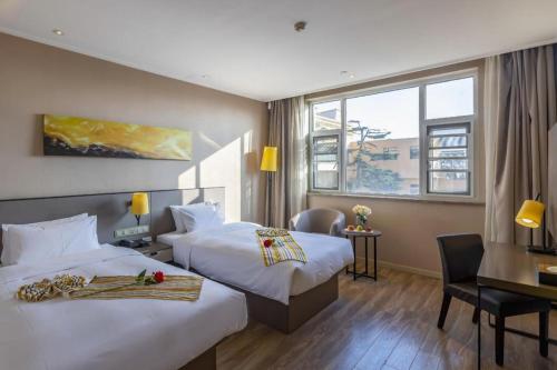 a hotel room with two beds and a desk at Yitel Tai'an Taishan Hongmen Daimiao in Tai'an