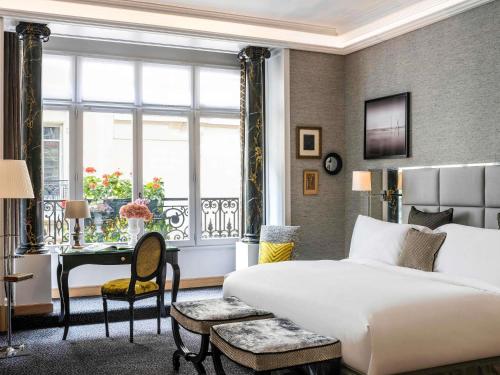 a bedroom with a bed and a desk and a window at Sofitel Paris Baltimore Tour Eiffel in Paris