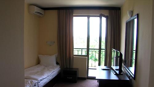 a bedroom with a bed and a window with a balcony at Motel Koziyat Rog in Malko Tŭrnovo