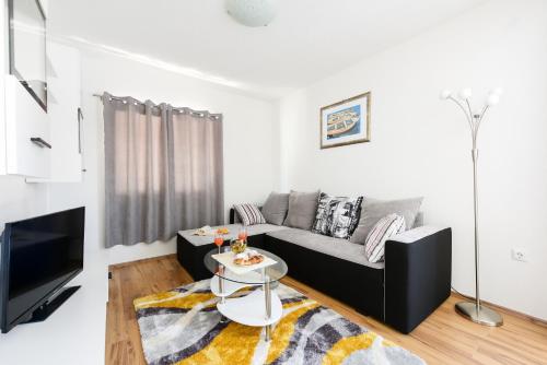 a living room with a couch and a tv at Holiday home Orange with heated pool and parking in Zadar
