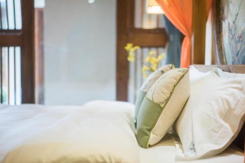 a bed with white sheets and pillows on it at Lijiang Yue Tu Inn in Lijiang
