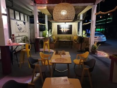 un ristorante con tavoli, sedie e TV di Vang Vieng Global Hostel a Vang Vieng