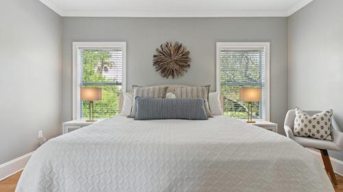 a white bedroom with a large bed and two windows at 3800 Cameron Boulevard AvantStay Pool Ocean Views Deck in Isle of Palms