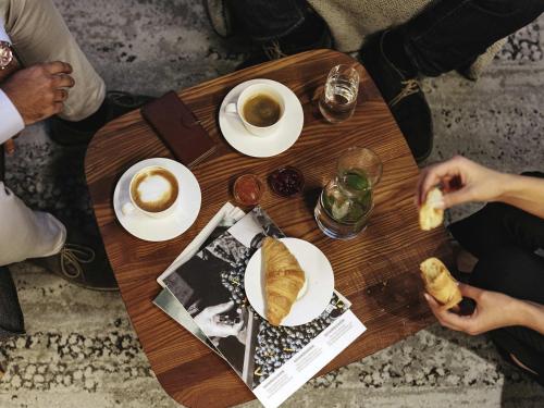 Un grupo de personas sentadas alrededor de una mesa de madera con café y pasteles. en Mercure Hotel am Messeplatz Offenburg, en Offenburg