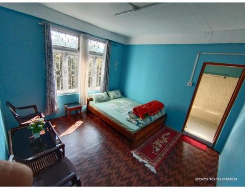 a blue room with a bed and a mirror at Ngima woizer Homestay,Tawang in Tawang