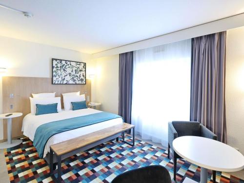 a hotel room with a bed and a table and chairs at Mercure Grenoble Centre Porte des Alpes in Grenoble