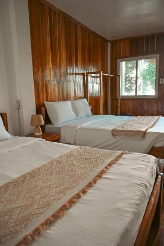 a bedroom with two beds with wooden walls and a window at Seaside Beach Hostel in San Vicente