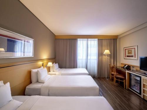 a hotel room with two beds and a television at Novotel Sao Paulo Center Norte in Sao Paulo