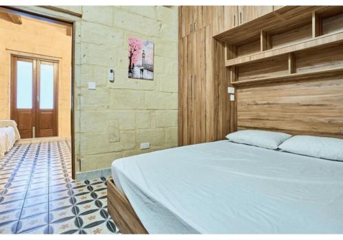 Un dormitorio con una cama grande con cabecero de madera. en Birgu's central traditional apartment, en Birgu
