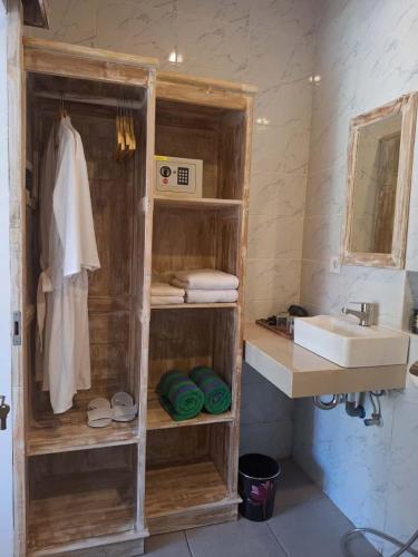 a bathroom with a sink and a shelf with towels at Casa Benoa Homestay in Nusa Dua