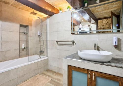 Un baño con lavabo, bañera y espejo. en Birgu's central traditional apartment, en Birgu