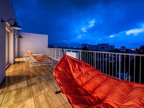 - un canapé rouge sur un balcon avec vue sur la ville dans l'établissement Mercure Marseille Centre Prado Vélodrome, à Marseille