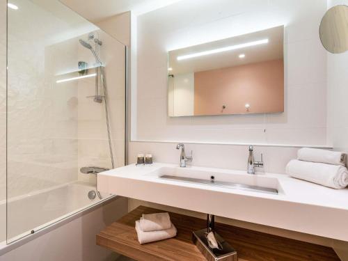 a white bathroom with a sink and a mirror at Mercure Marseille Centre Prado Vélodrome in Marseille